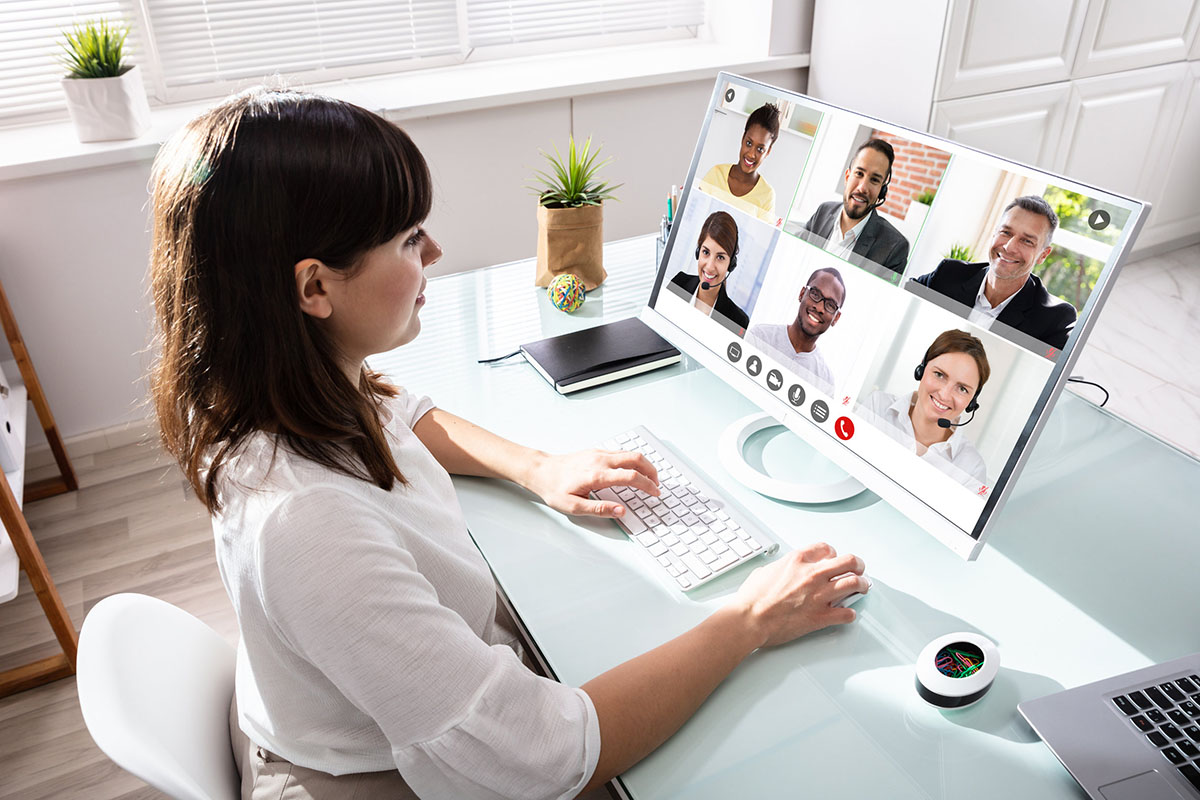 Business woman in video conference with co-workers over laptop computer in home office.